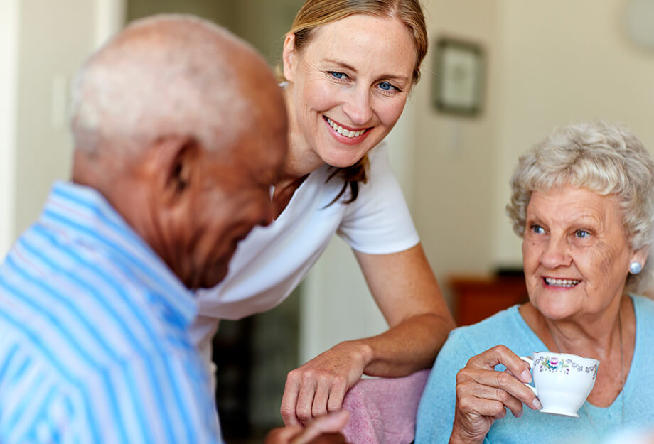 Friendly caregiver interacting with seniors in a cozy living space.