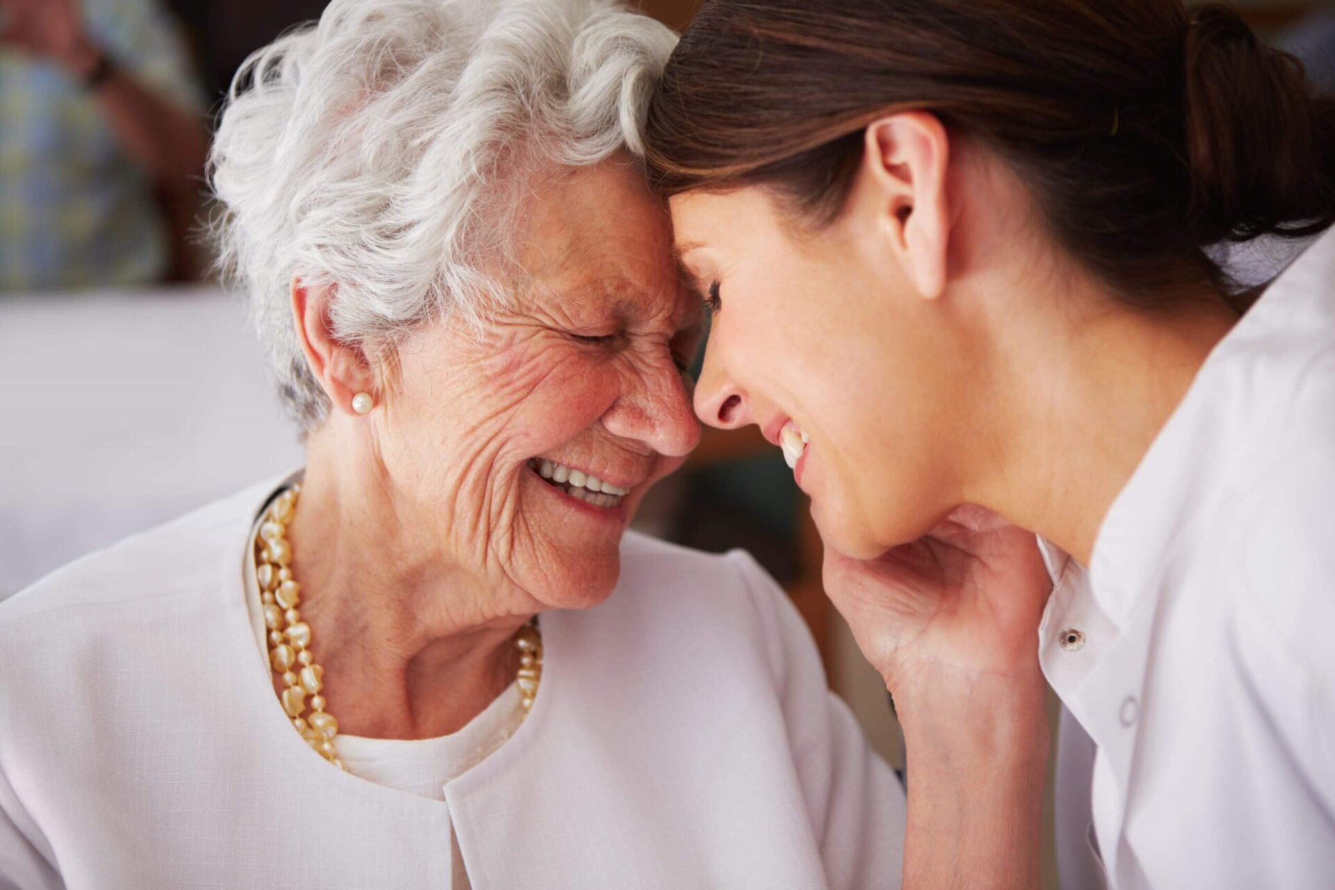 Elderly woman and caregiver sharing a joyful, affectionate moment.