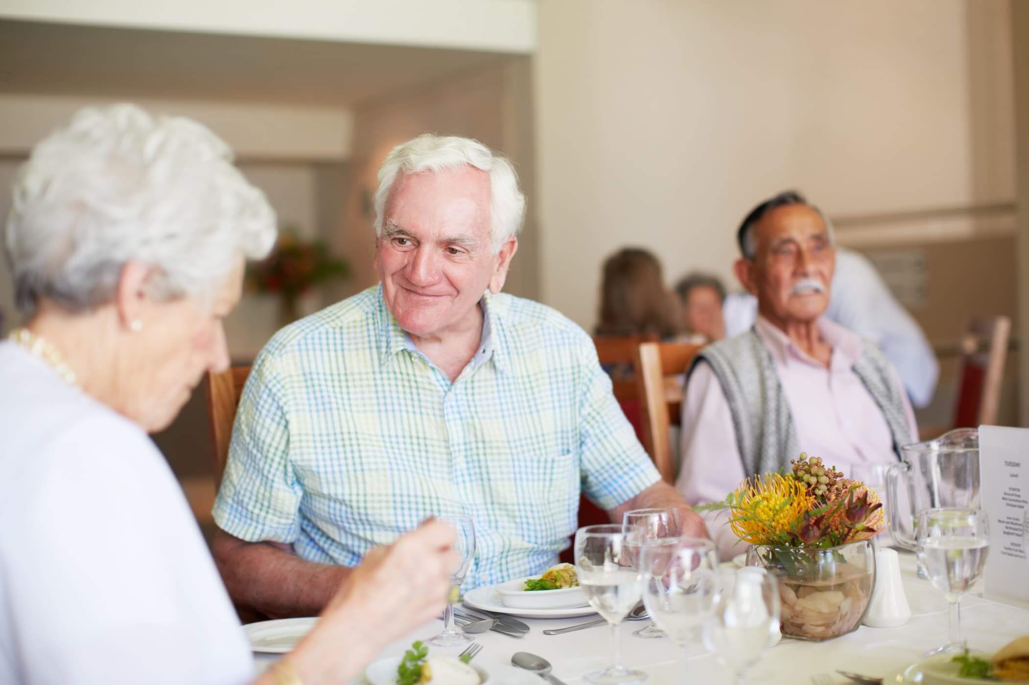 Elderly residents enjoying a meal together in a communal dining area.