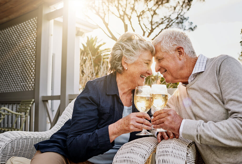 Elderly couple enjoying wine on patio of a living community.