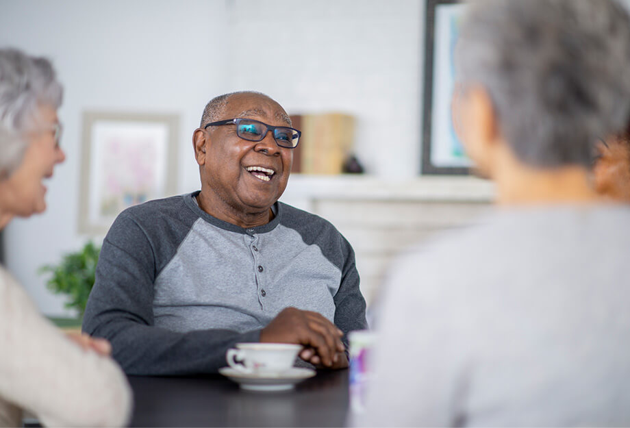 Elderly individuals enjoy a conversation in a community setting, smiling together.